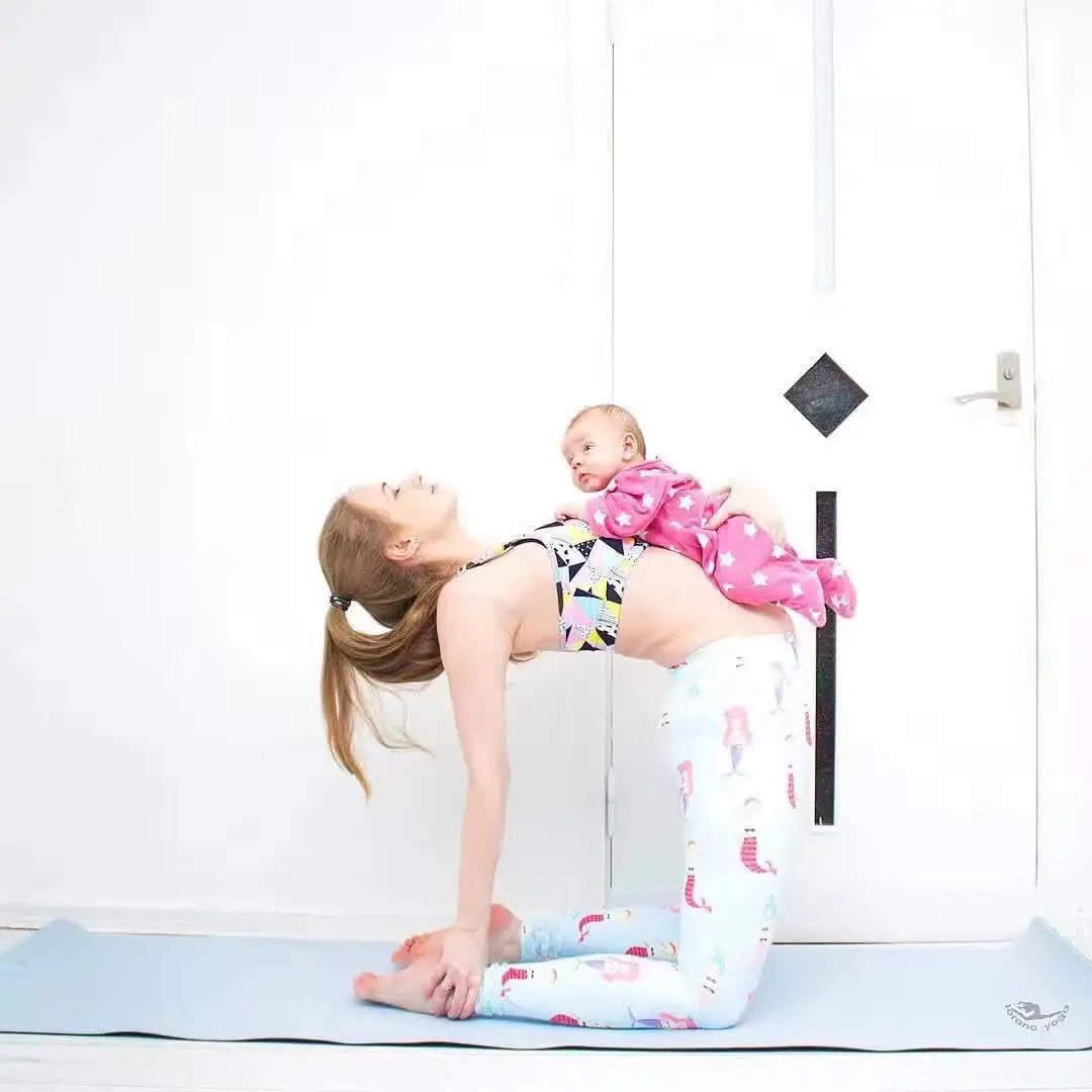 Woman practicing yoga with a baby on her back wearing Beauty Fitness Yoga Pants.