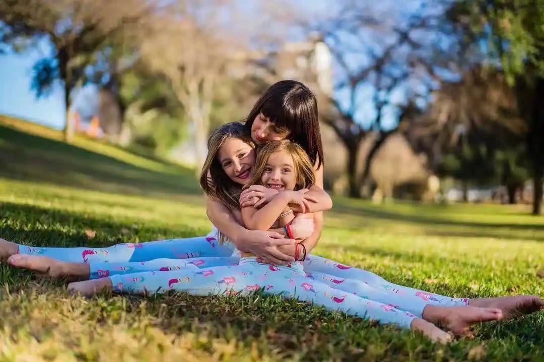 Mother and daughters wearing beauty fitness yoga pants in a park setting.