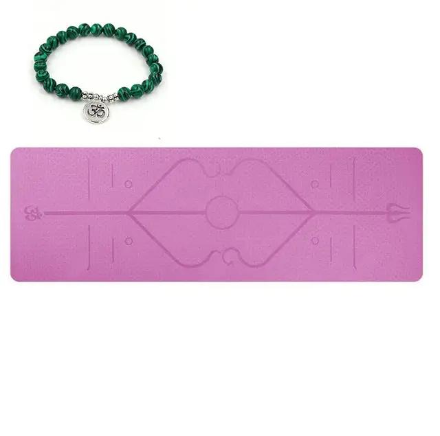 Pink yoga mat with printed position lines and green bracelet, made from eco-friendly TPE material.