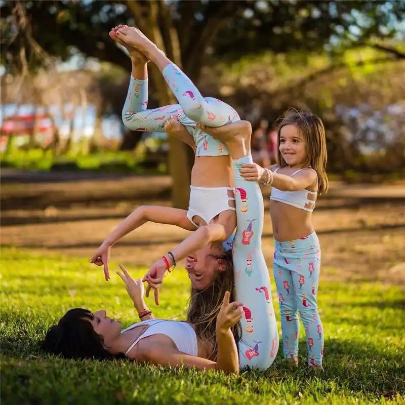 Family enjoying yoga in matching beauty fitness yoga pants in a park.