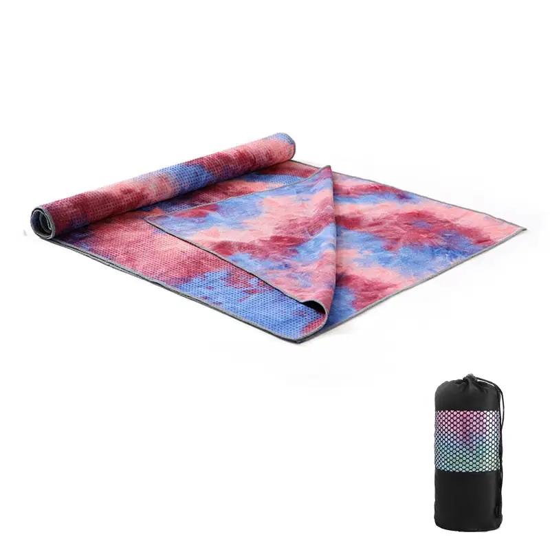 Tie-dye yoga blanket pad towel with vibrant colors, rolled for display, alongside a carrying bag.