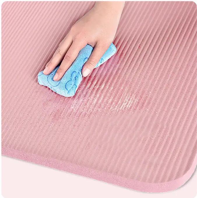 Pink TPE yoga mat with a hand wiping it clean, ideal for home fitness.