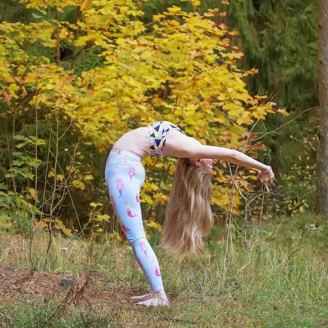 Woman practicing yoga outdoors in beauty fitness yoga pants with colorful pattern.