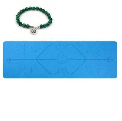 Blue TPE yoga mat with printed position lines and green beaded bracelet.