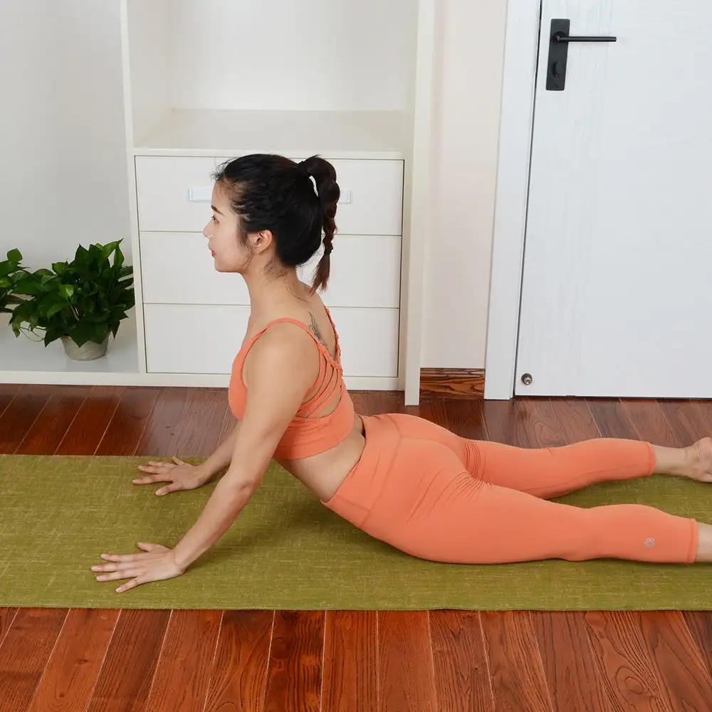 Person practicing yoga on anti-slip sports yoga mat, PVC and linen material, green color, suitable for fitness and martial arts.