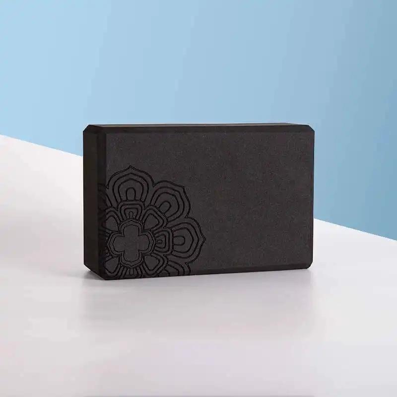 Black yoga brick with mandala design on a light surface.