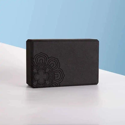 Black yoga brick with mandala design on a light surface.