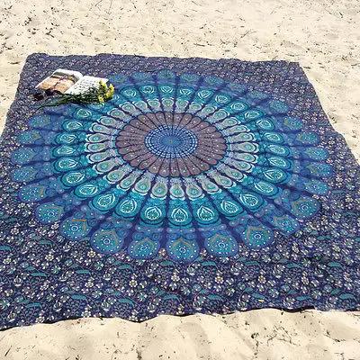 Colorful mandala-patterned yoga mat on sandy beach.