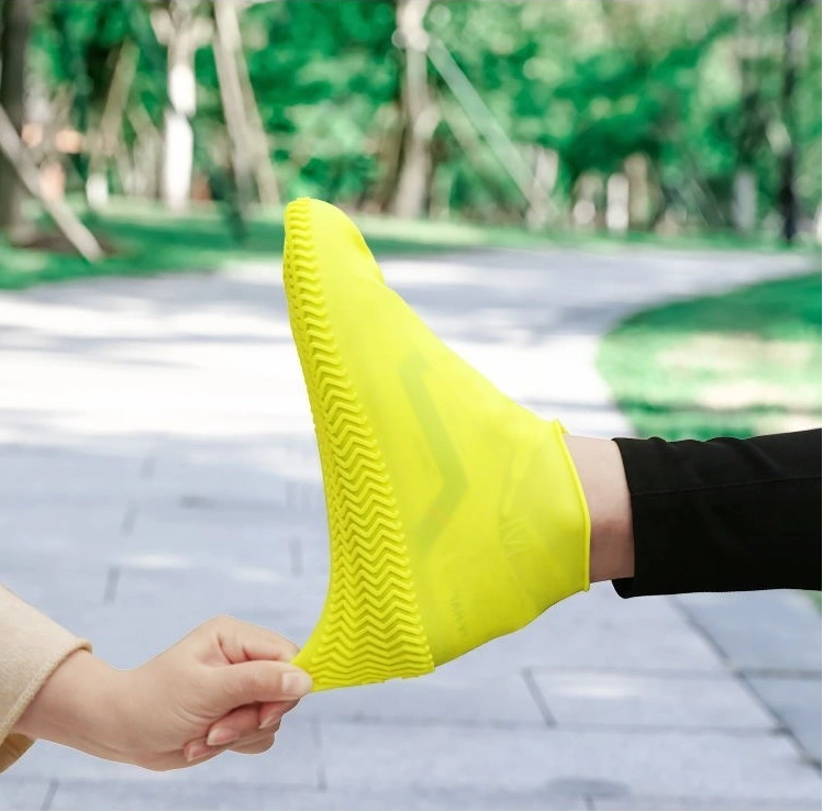 Bright yellow silicone rain boot, slip-resistant and easy to carry for hiking, being demonstrated outdoors.