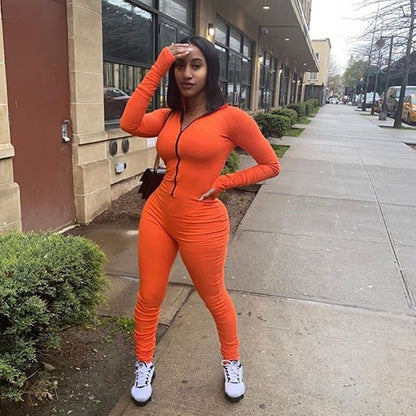 Turtleneck gloved sleeve jumpsuit leggings in vibrant orange worn outdoors.